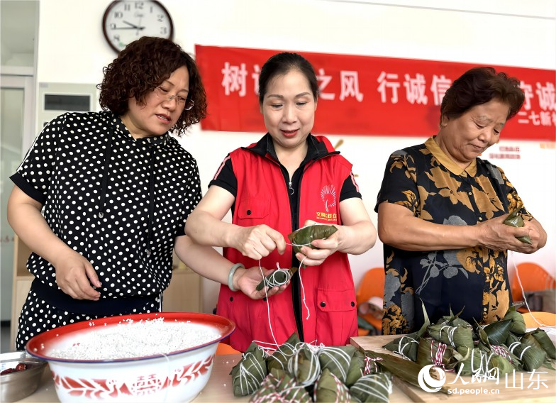 6月21日，濟南市市中區二七新村街道建南社區舉行“鄰里家和美，端午祝安康”活動。社區居民聚在一起包粽子、迎端午。人民網 喬姝攝
