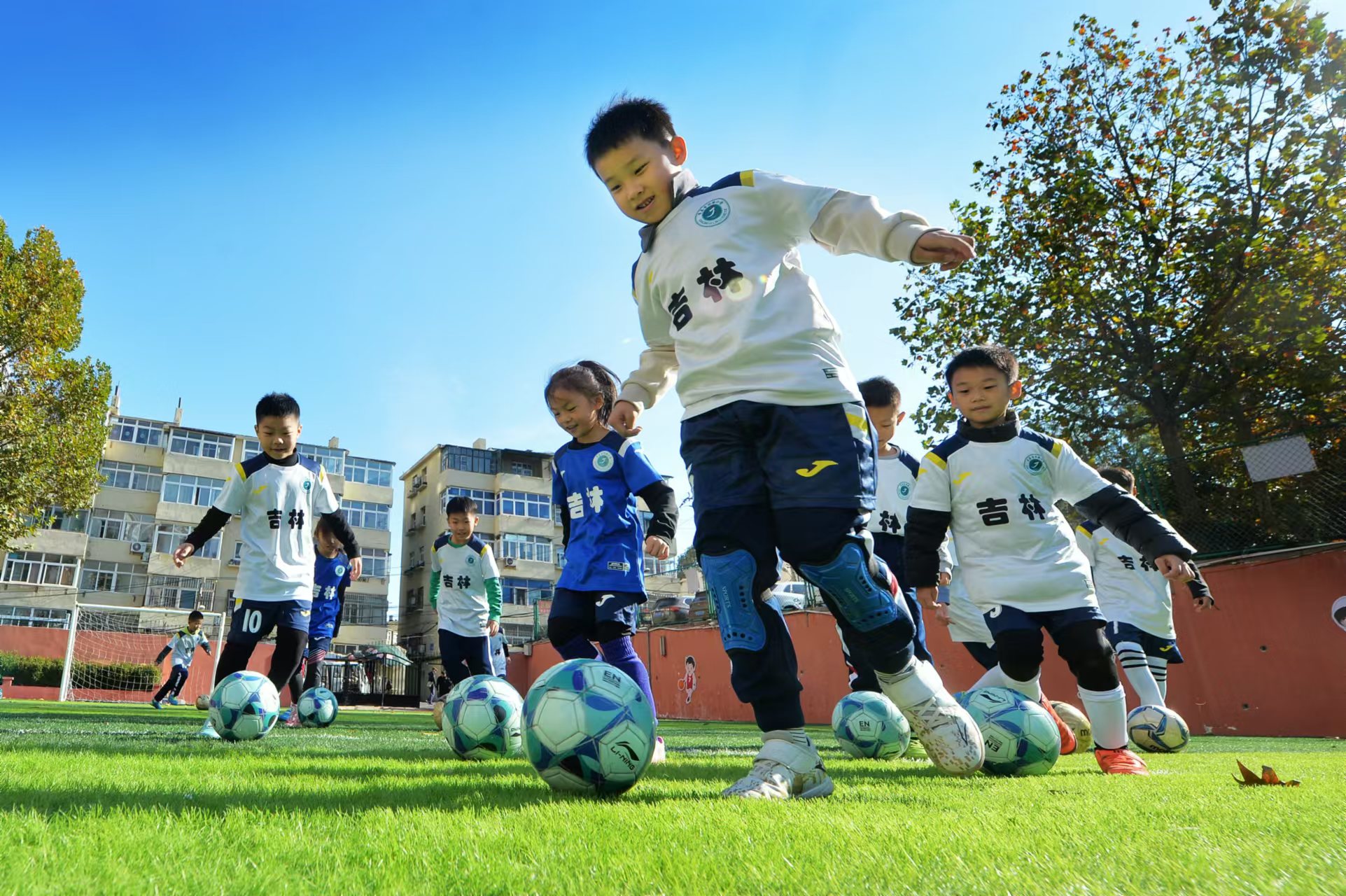 2024年11月18日，在山東青島吉林路小學開展的足球冬訓活動上，孩子們在綠茵場上進行帶球訓練。