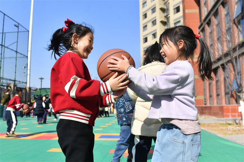 兩名小朋友在山東青島高安路幼兒園開展的新學期“悅動健康”主題課堂上玩籃球游戲。王海濱攝