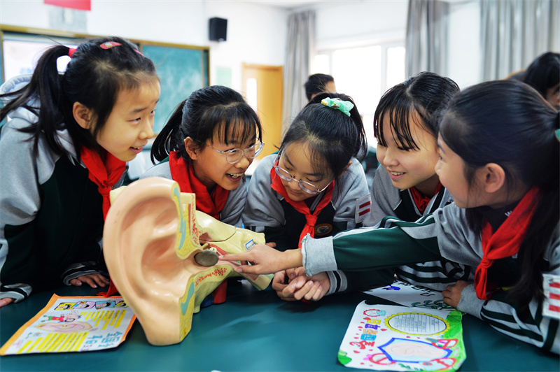 在山東青島市北實驗小學、無棣四路小學開展的“全國愛耳日”活動上，學生們在觀看耳朵構造模型。