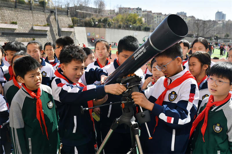 2025年3月13日，在山東青島寧安路小學開展的天文主題科普教育活動上，學生們在體驗天文望遠鏡。
