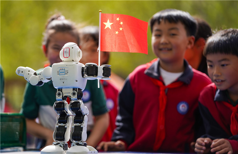 2025年4月16日，山東省樂陵市市中街道阜平小學科技勞動周現場，小學生在觀看遙控“機器人”秀。
