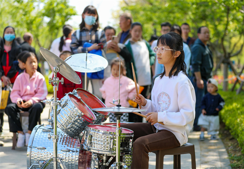 4月20日，一小朋友在山東青島萊西市月湖公園給游客表演架子鼓。張進剛攝